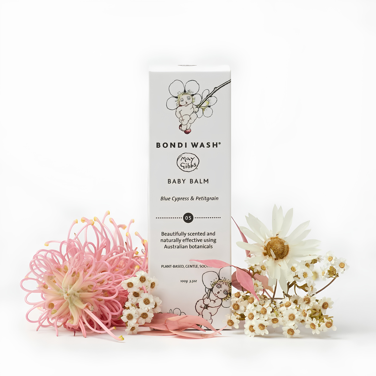 Bondi Wash Baby Balm box standing upright on a white background, styled with pink and white flowers in front. The box is white with black text and floral line art, and the product name reads Baby Balm with Blue Cypress & Petitgrain.