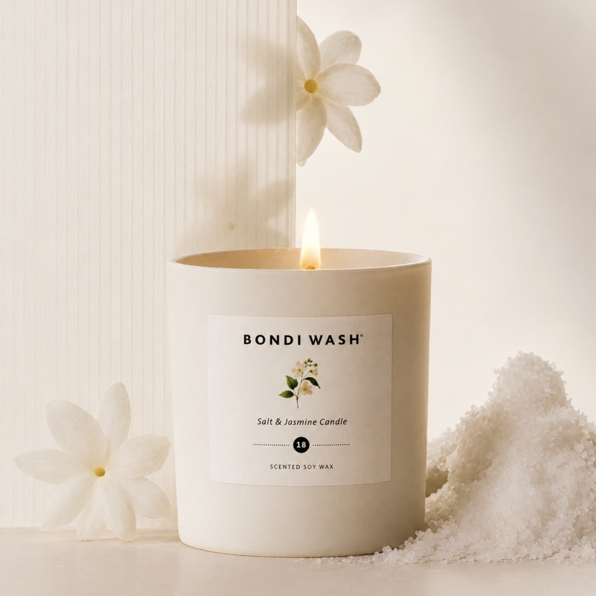 Bondi Wash scented soy wax candle with salt jasmine aroma, featuring a sleek glass container and a lit wick.