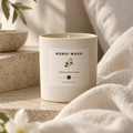 Bondi Wash scented soy wax candle with salt and jasmine fragrance, in a glass container with a lit wick.