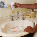 Person washing a pink garment in a sink with soap and water, using a bottle of Bondi Wash Lingerie Wash.