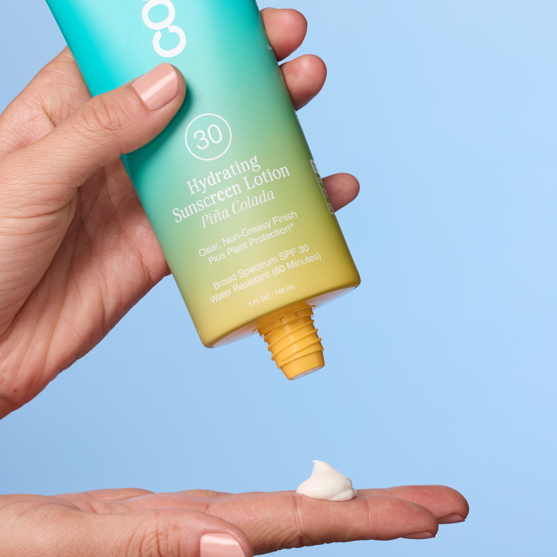 A hand holds a teal-to-yellow gradient tube of COCO Hydrating Sunscreen Lotion Pina Colada SPF30 above another hand showing a dollop of white lotion, against a light blue background.