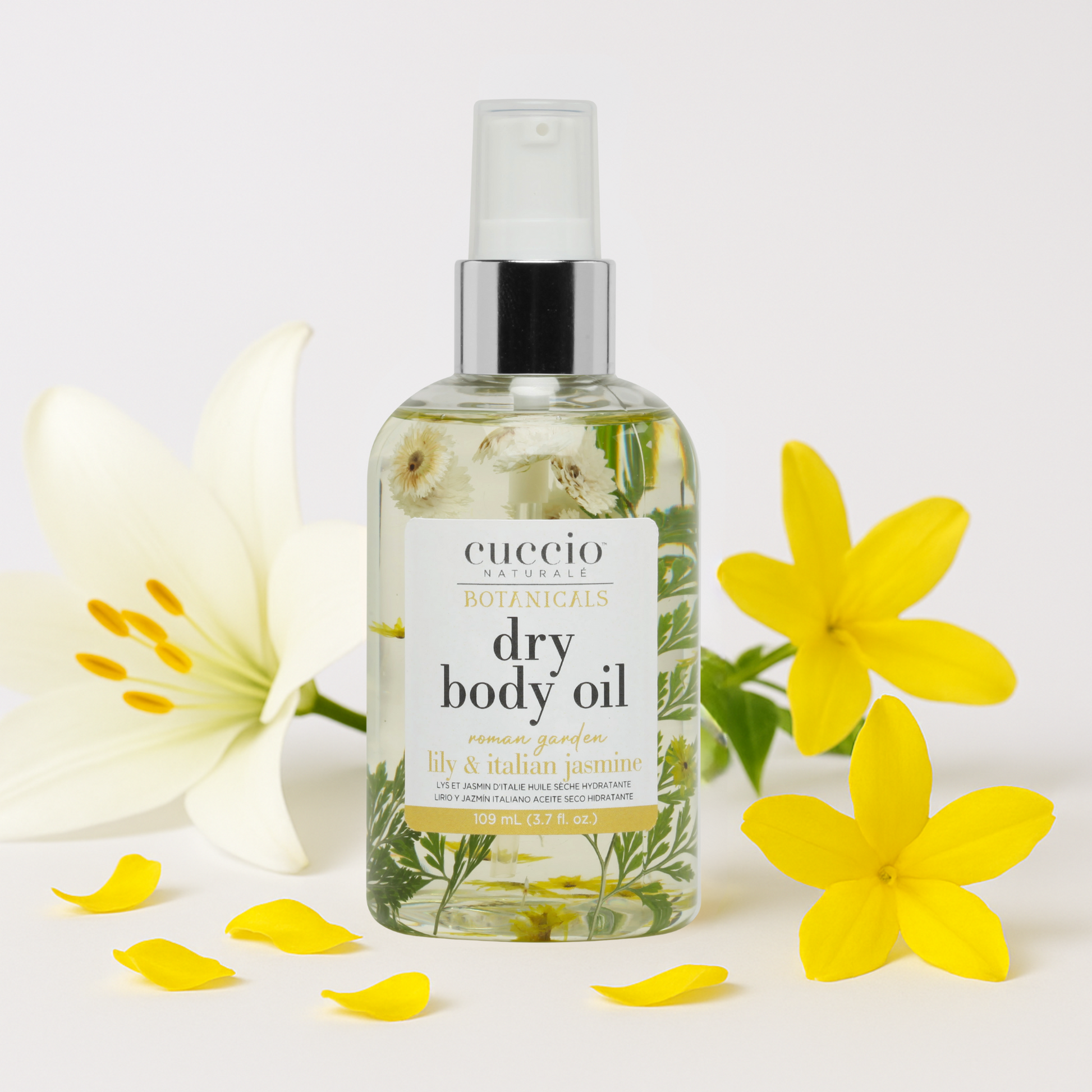 Cuccio dry body oil bottle with lily and Italian jasmine petals flowers on a white background