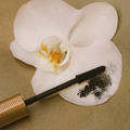 Eco by Sonya Driver Mitzi Mascara wand on a white orchid flower against a beige background
