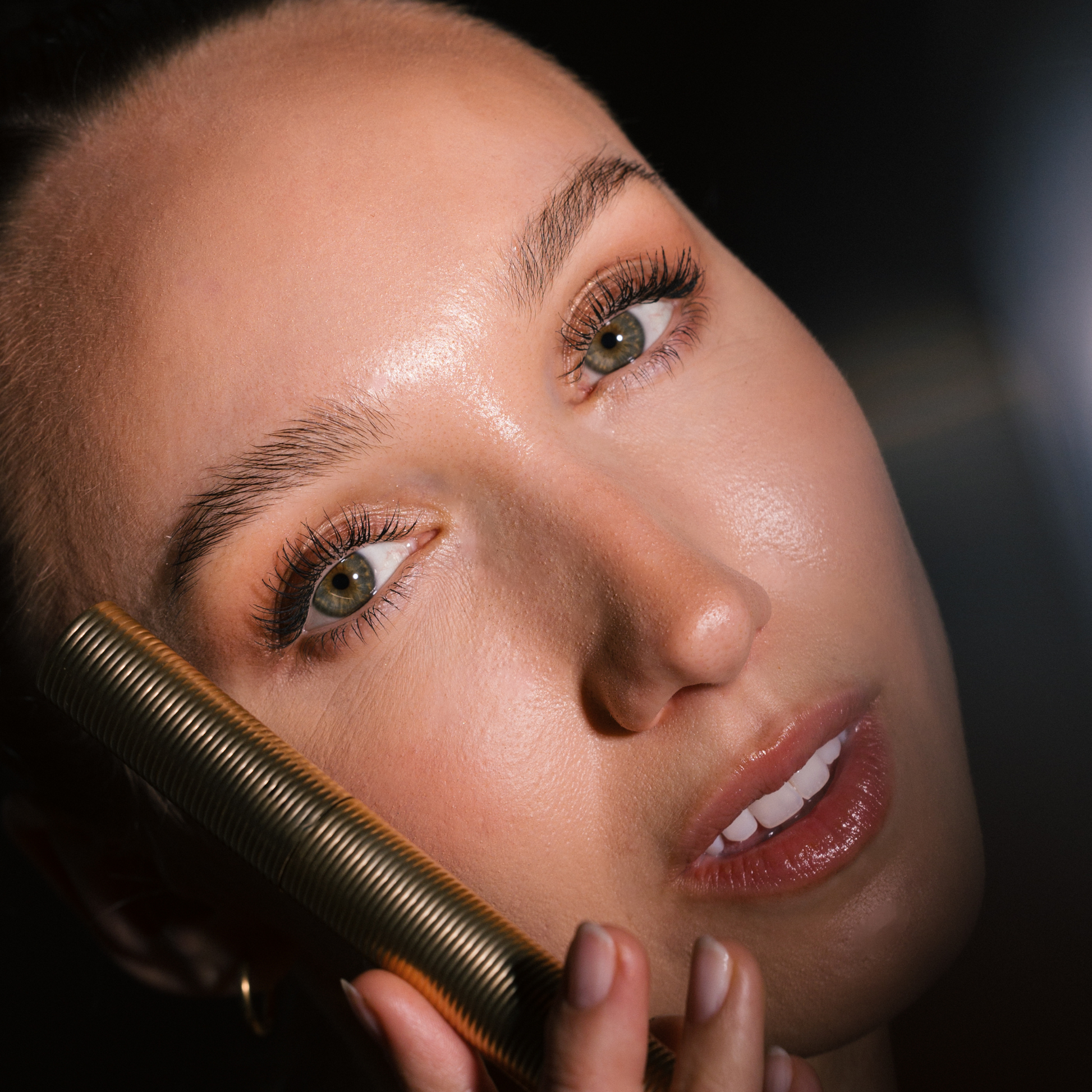 Close-up of a woman applying Eco by Sonya Driver Mitzi Mascara on a dark background