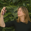 Woman holding a Super Fruit Essence bottle against a green leafy background