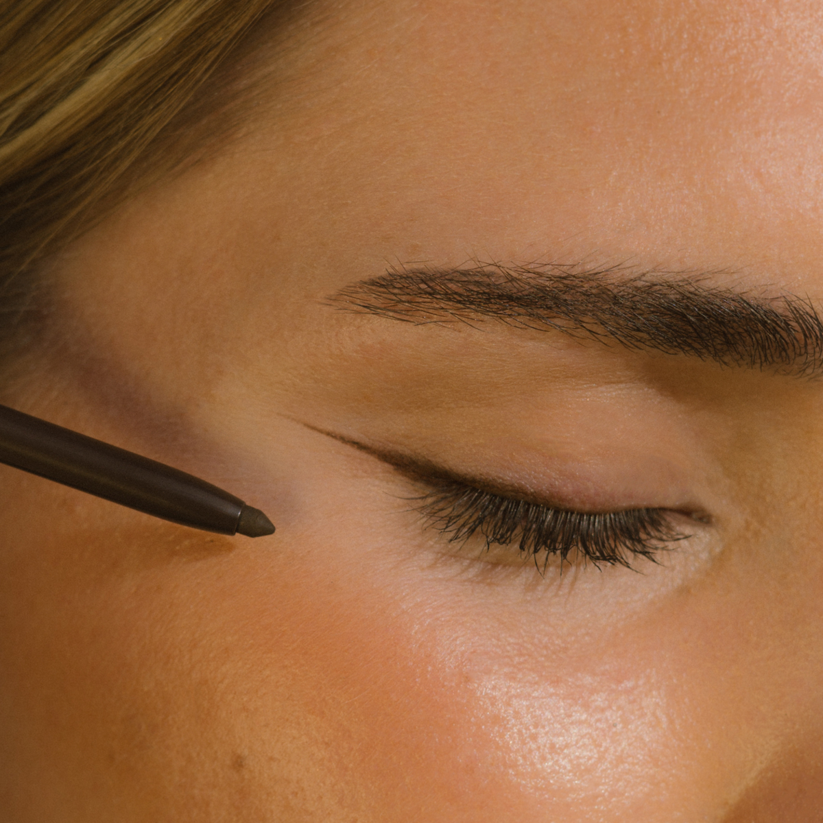 Close-up of a person applying Eco by Sonya Rich Brown eyeliner.