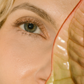Close-up of a woman's eye wearing Eco by Sonya mitzi brown mascara with a decorative headpiece