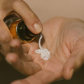 Hand holding a bottle of skincare product with a small amount of white Super Fruit Hydrator cream on an open palm