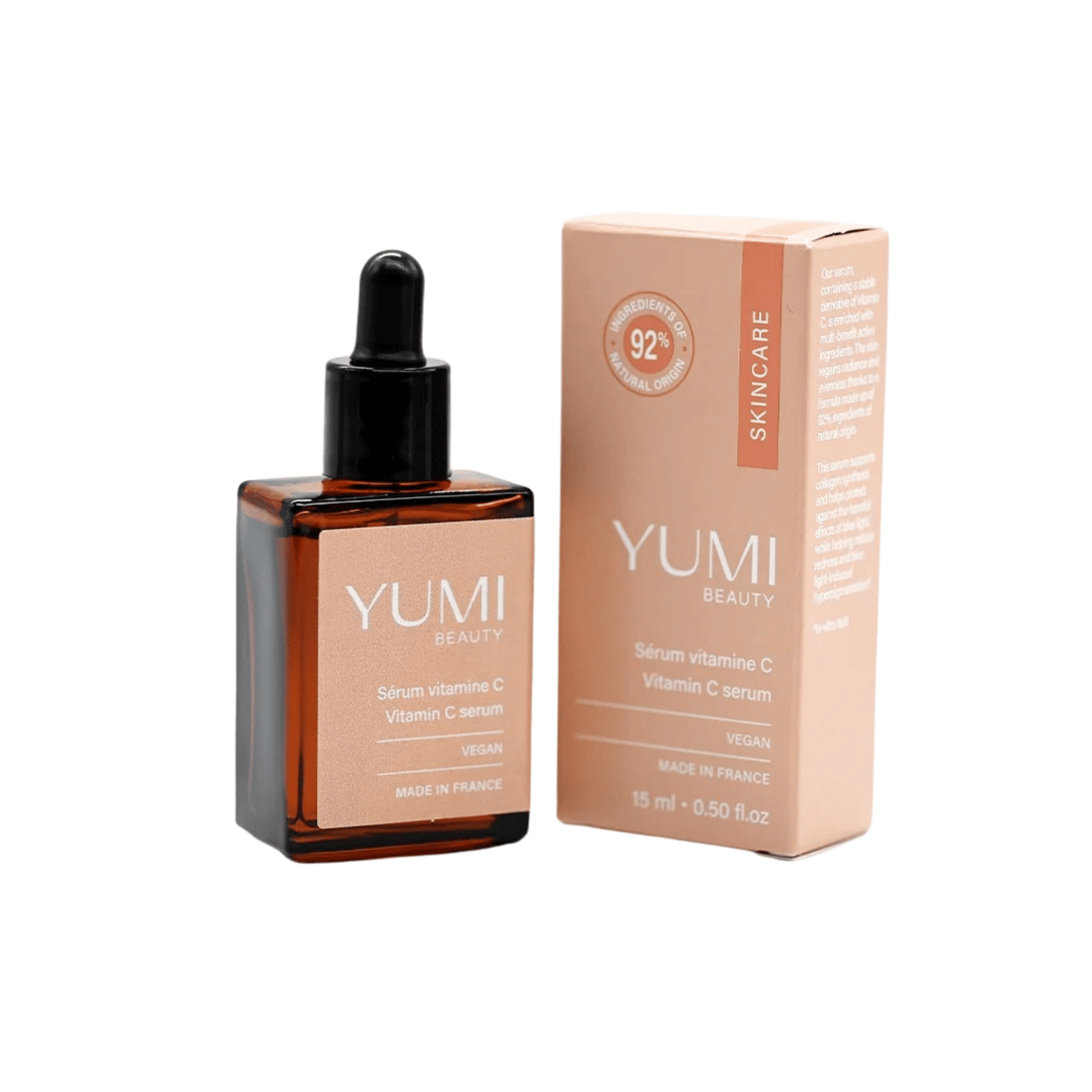 Yumi Beauty Vitamin C Serum in an amber glass dropper bottle next to its peach-colored packaging box, on a solid white background.