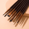 Élan Cosmetics professional makeup brush face #27 for lashes and brows, with soft bristles and ergonomic handle, shown in a lifestyle setting.