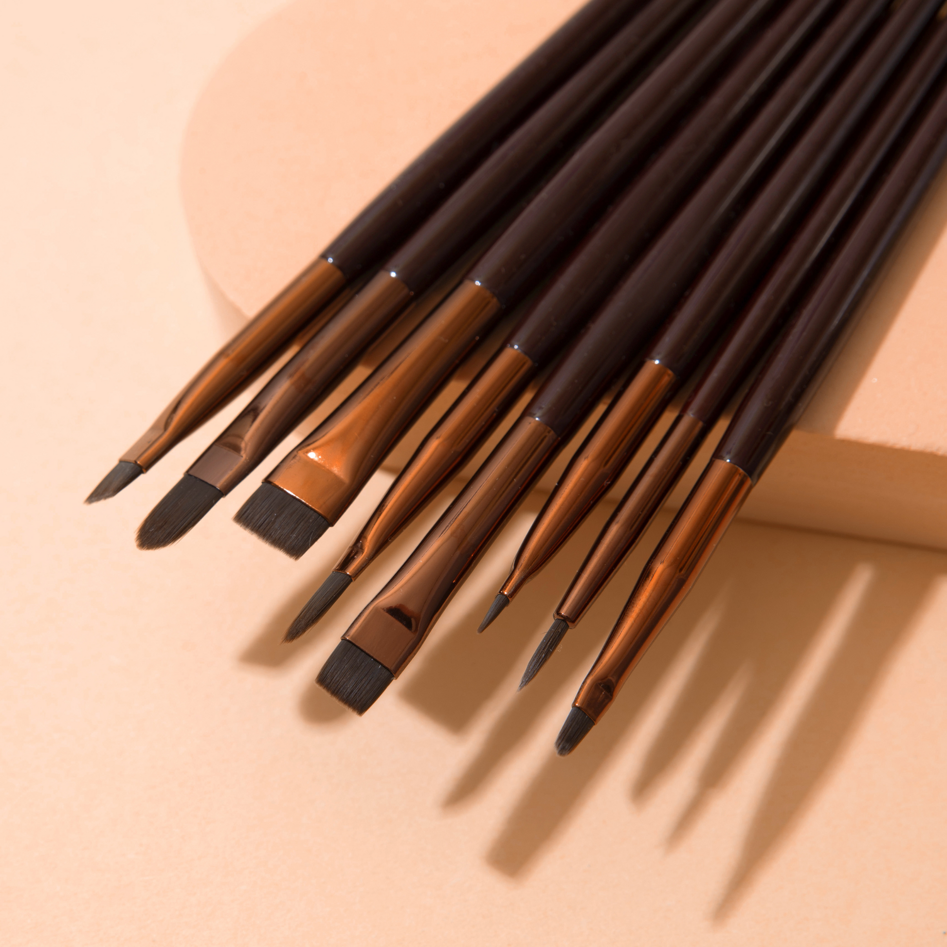 Élan Cosmetics professional makeup brush face #27 for lashes and brows, with soft bristles and ergonomic handle, shown in a lifestyle setting.