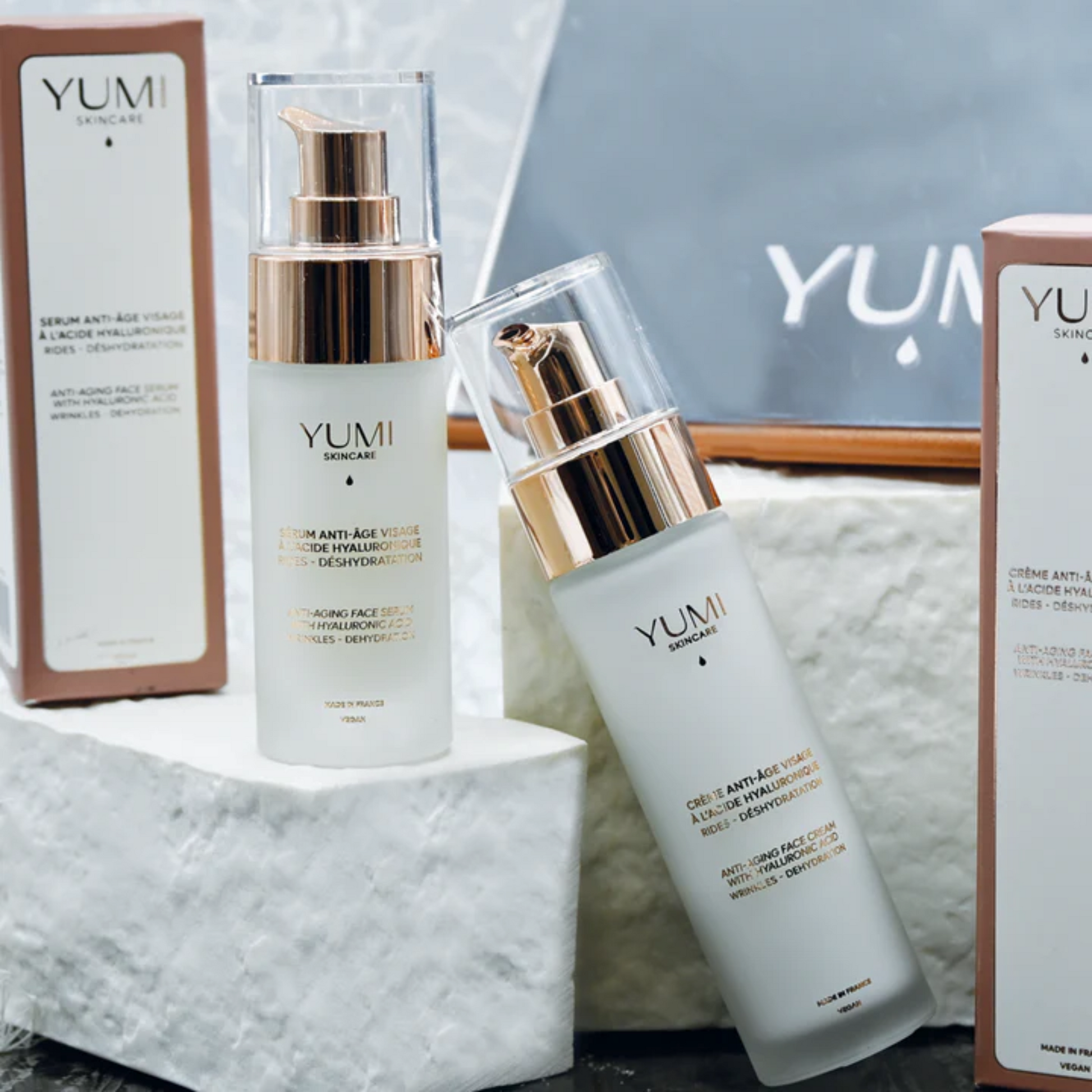 YUMI skincare products on a marble surface with a blurred background