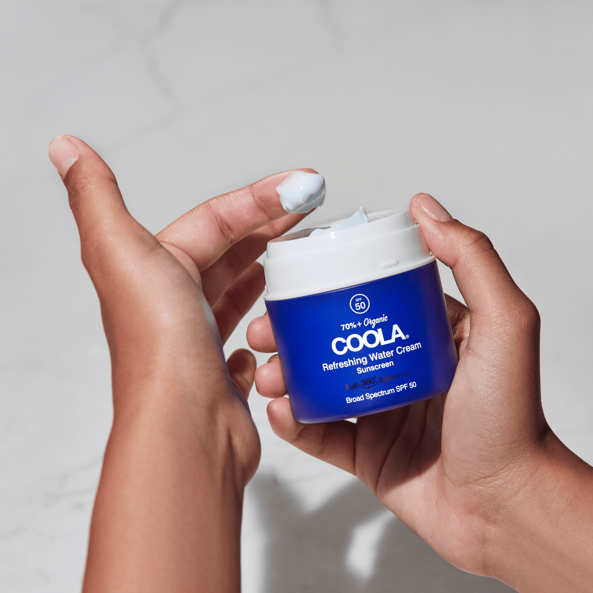 Coola Refreshing Water Cream Organic Face Sunscreen SPF 50 lotion in a white jar with blue labeling, showing the moisturizer texture.