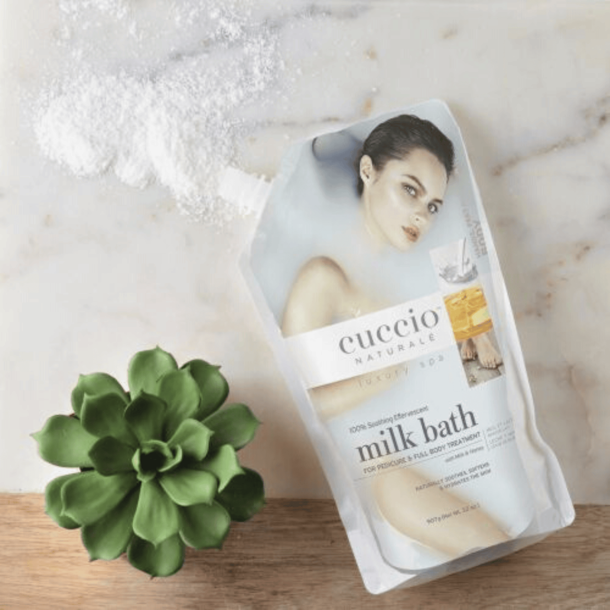 Creamy Cuccio Naturalé Milk Bath in a glass jar with a scoop, designed for relaxing bath and body skincare.